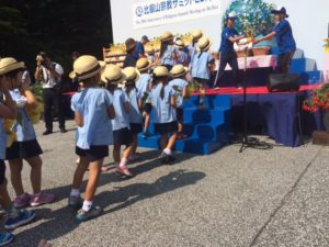 School children carrying cranes made by them to fill up the globe on display on the stage.